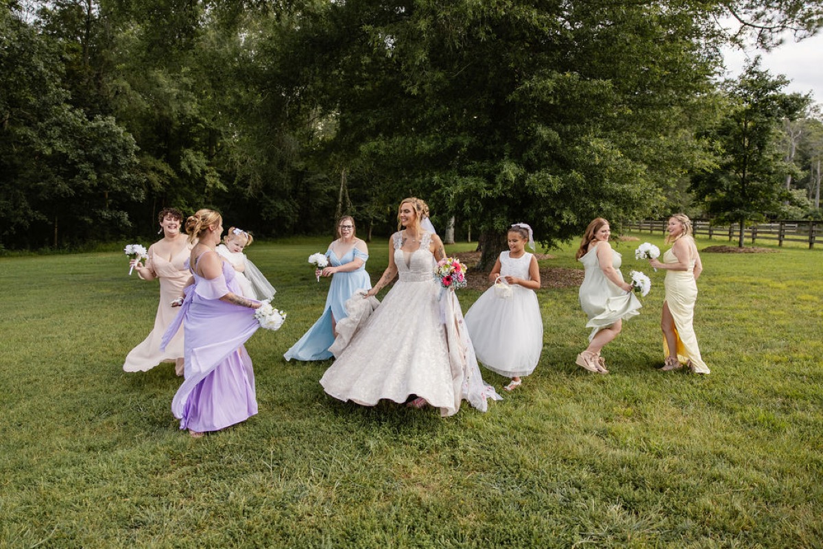 Kolbe and pastel bridesmaids twirl with flower girls on the lawn at Covey Creek for Kolbe & Nathan