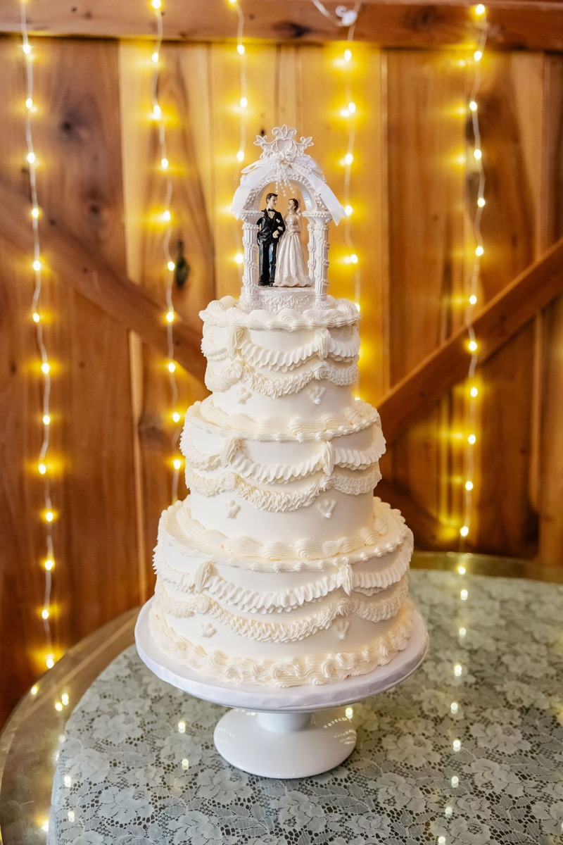 Three-tier white wedding cake with bride-and-groom topper for Kolbe & Nathan at Covey Creek