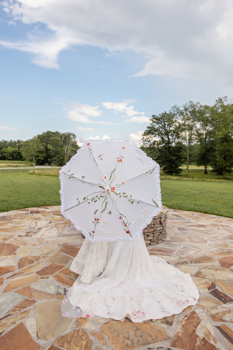 Kolbe faces away under a Mrs. Brokaw parasol with floral train on the patio at Covey Creek for Kolbe & Nathan