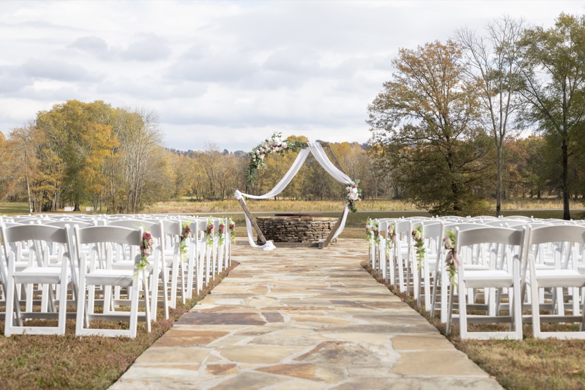 Kristen & Dalton Firepit ceremony setup with hexagonal wood arbor, white chairs, and autumn trees at Covey Creek