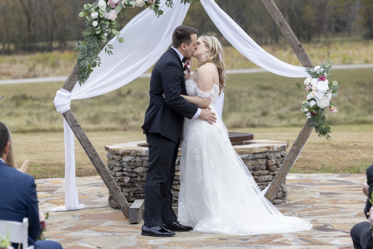 Kristen & Dalton share their first kiss under a floral hexagonal arbor at the Firepit ceremony at Covey Creek