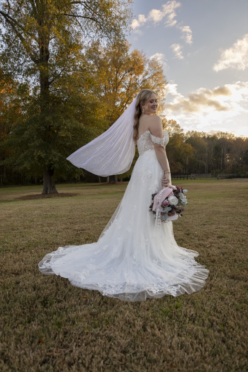 Kristen & Dalton bridal portrait: lace gown, pearl veil blowing, bouquet at golden hour in a field at Covey Creek
