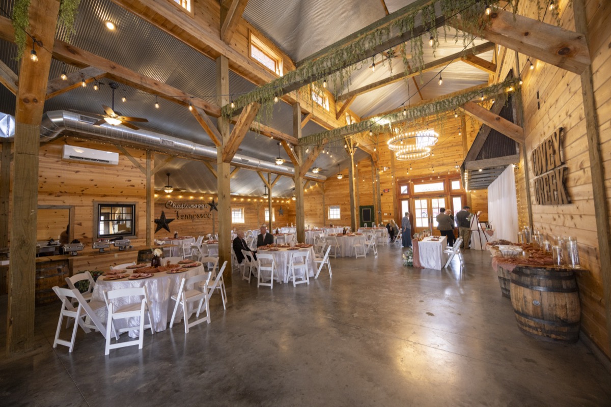 Covey Creek barn reception set for Kristen & Dalton with white tables, string lights, and wooden venue signage
