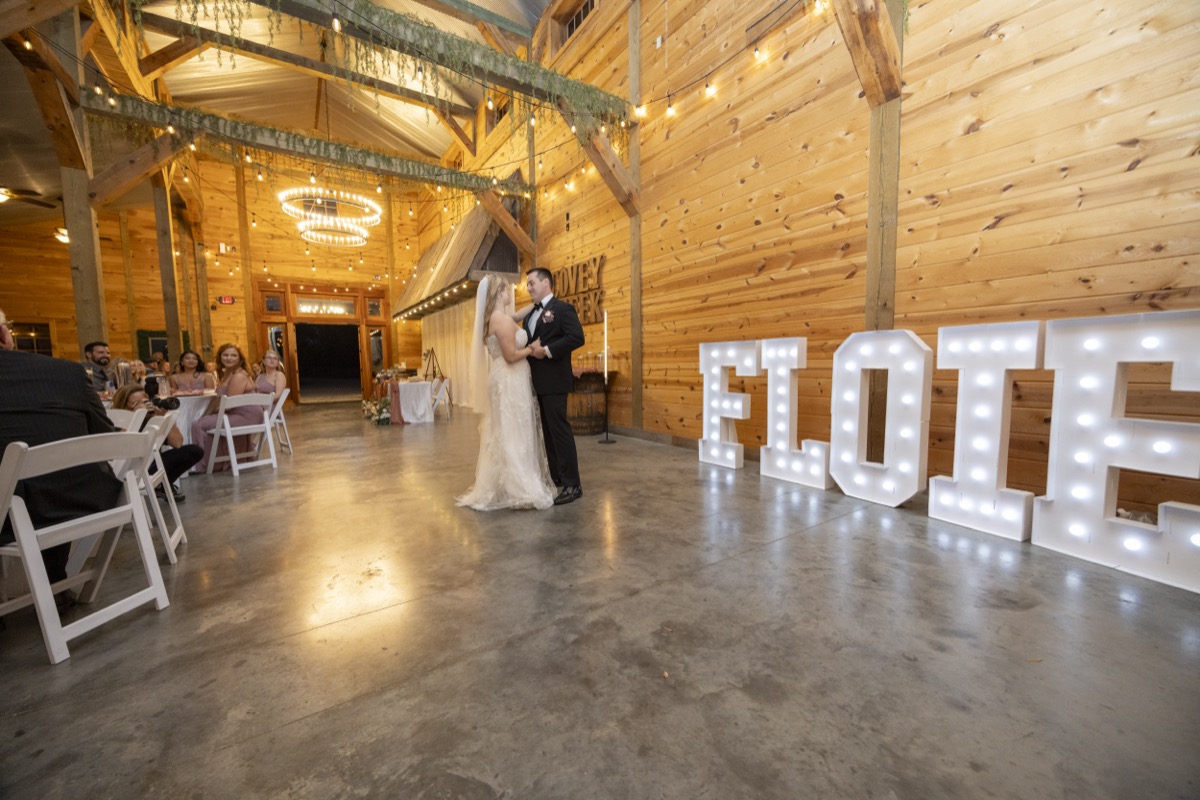 Kristen & Dalton share their first dance beside ELOPED marquee letters under barn string lights at Covey Creek