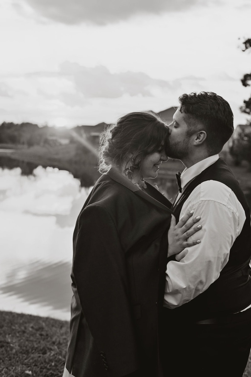 Lauren & Alex share a forehead kiss by the pond at sunset in black and white at Covey Creek