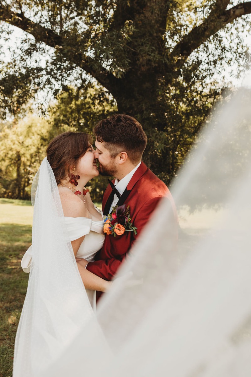 Lauren & Alex touch noses and smile close, her dotted veil framing them outdoors at Covey Creek