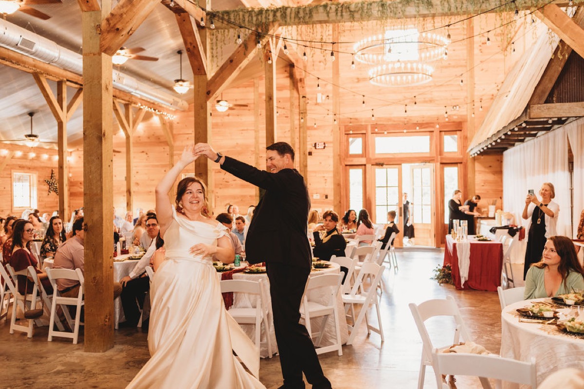 Lauren & Alex spin together under string lights and chandeliers in the barn at Covey Creek