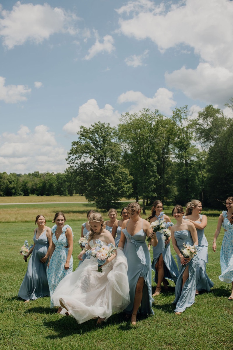 Leah & Gordon’s bridal party walks the Covey Creek lawn, blue dresses and white floral bouquets bright
