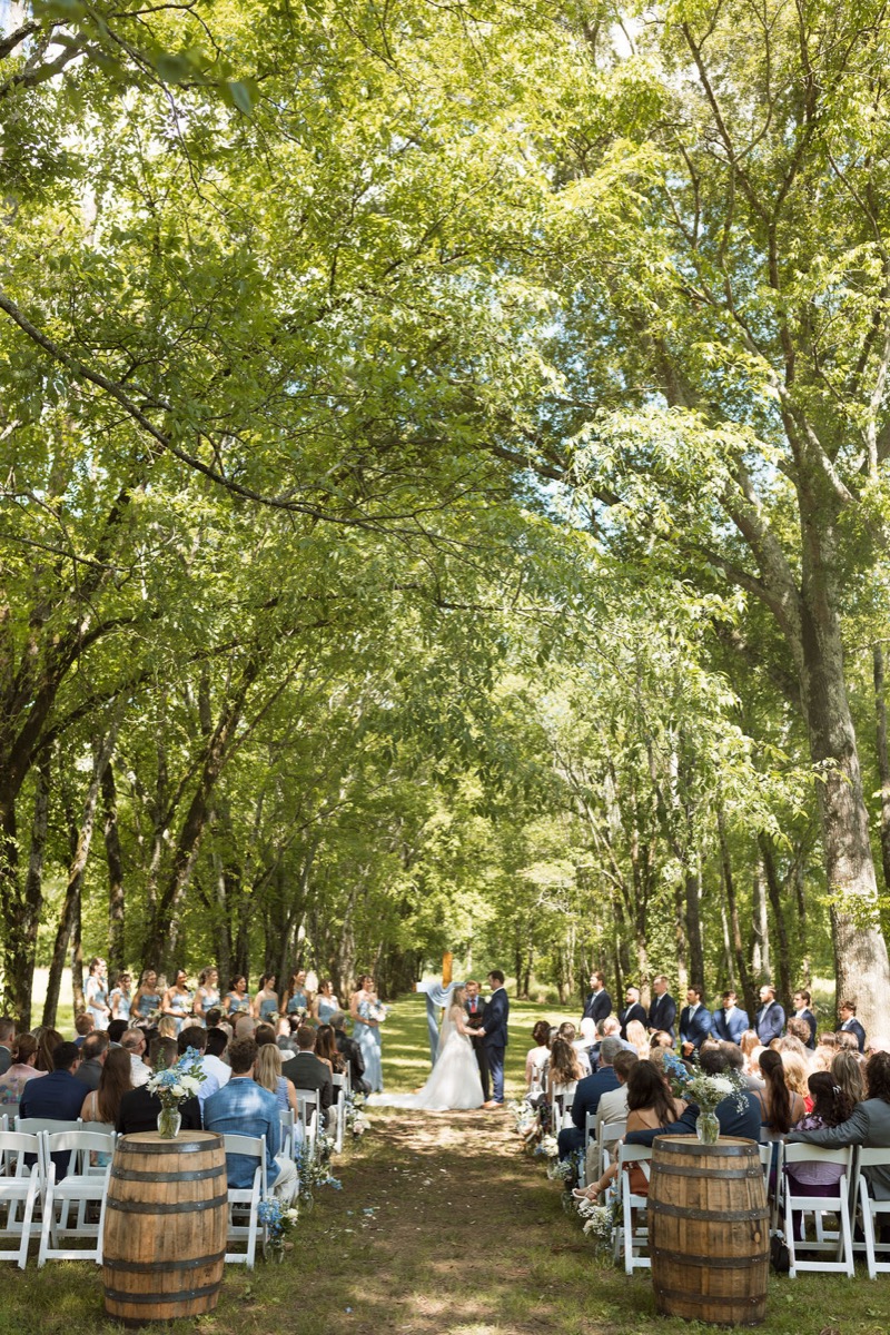 Leah & Gordon’s Tunnel of Love ceremony at Covey Creek, barrel florals framing the tree-lined aisle