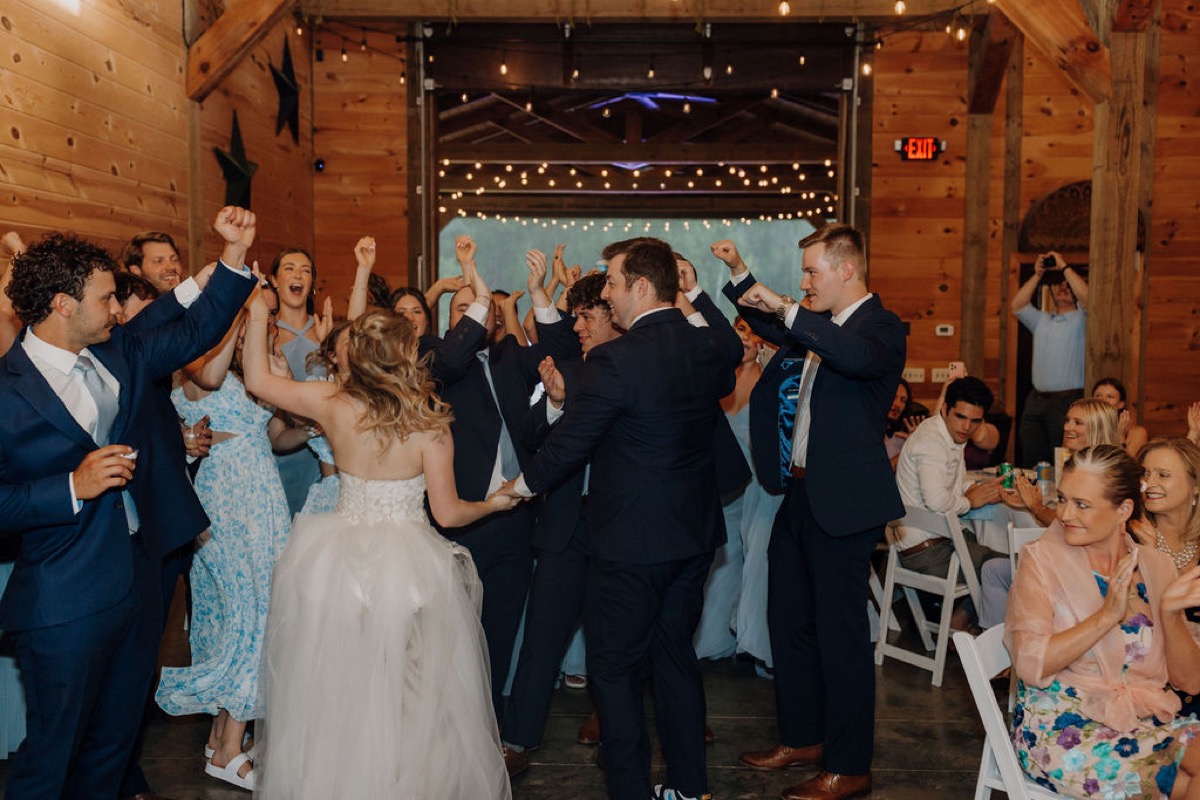 Leah & Gordon dance as guests cheer in Covey Creek’s wood-beamed barn under warm string lights