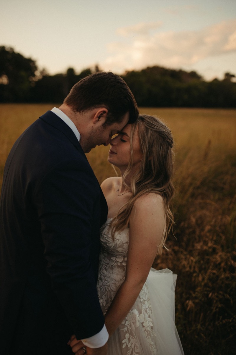 Leah & Gordon touch foreheads in tall golden grass at Covey Creek during soft golden-hour light