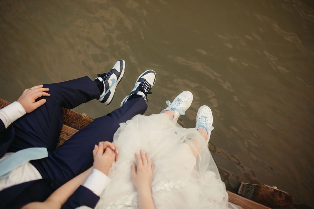 Leah & Gordon sit on Covey Creek’s Pond dock, sneakers dangling over the water as they hold hands