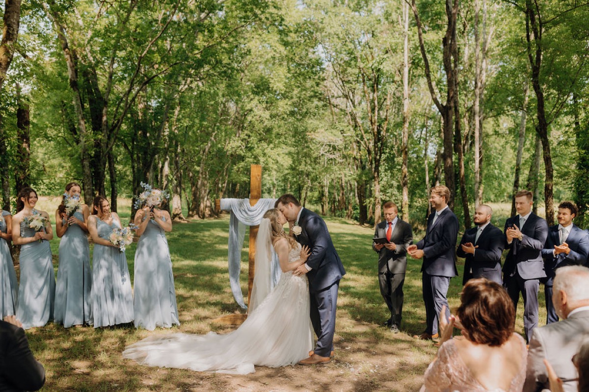 Leah & Gordon share their first kiss under Covey Creek’s trees as the bridal party cheers beside them