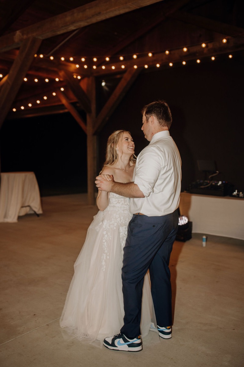 Leah & Gordon slow dance under string-lit timber beams at Covey Creek beside the outdoor DJ booth