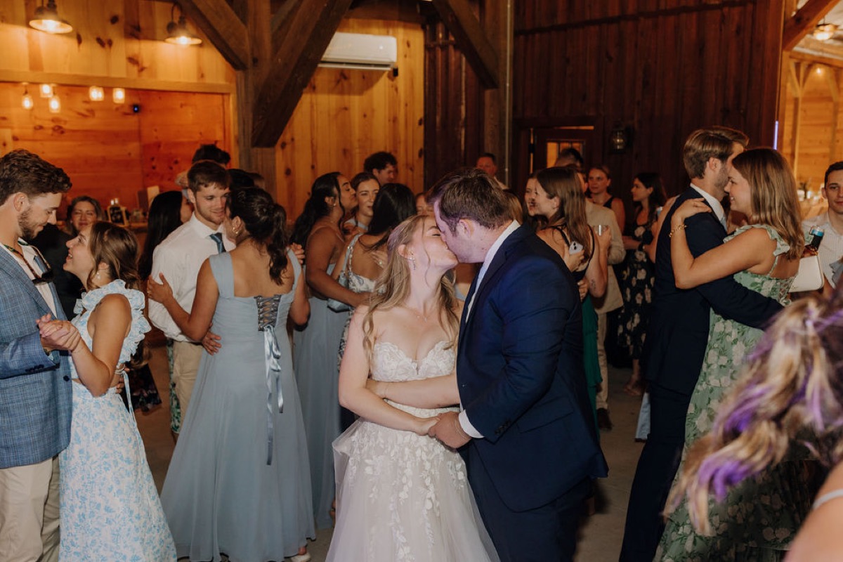 Leah & Gordon kiss while dancing among guests in Covey Creek’s warm wood-paneled reception barn