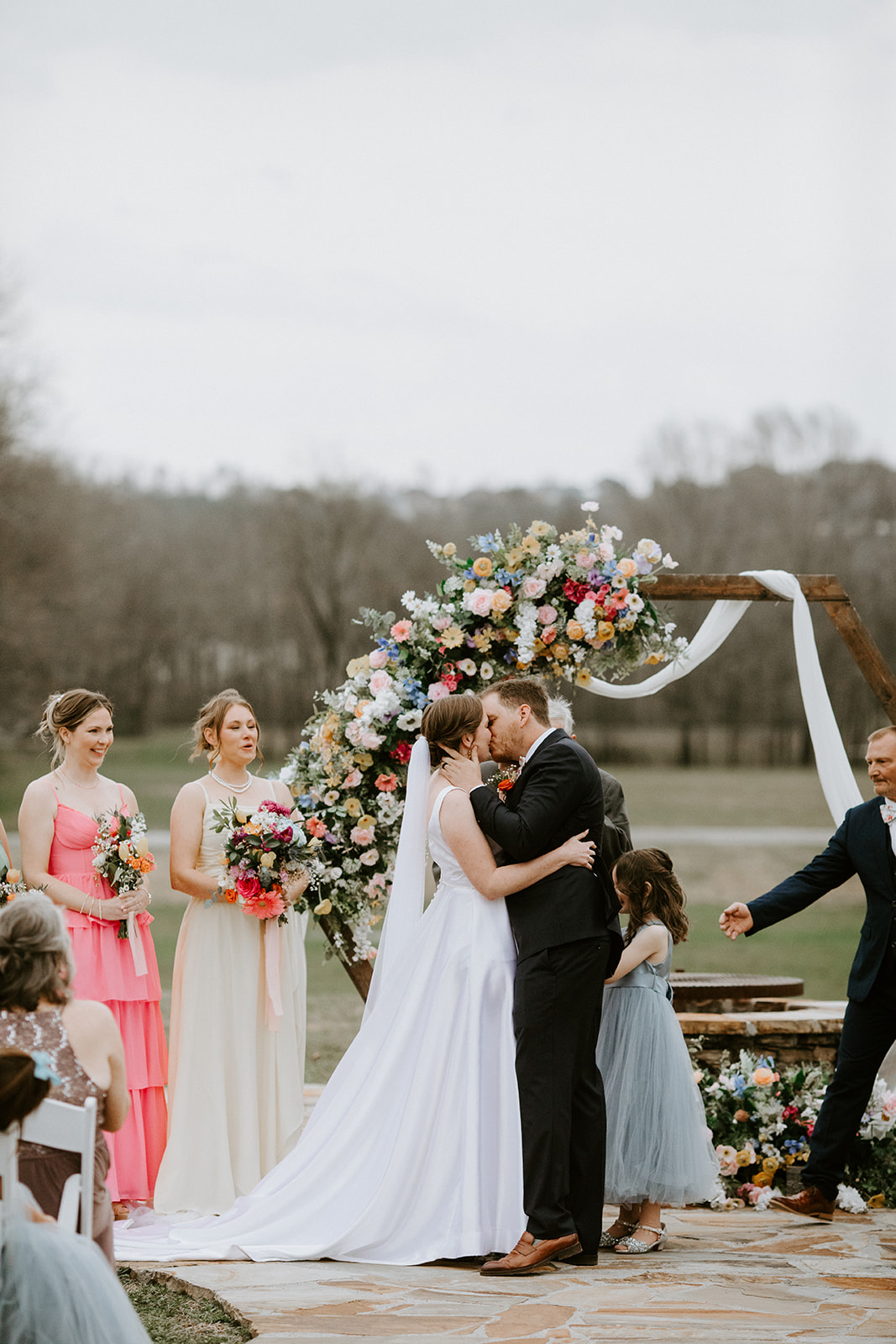 Leslie & Timothy share first kiss under floral hexagon arch on Covey Creek flagstone patio