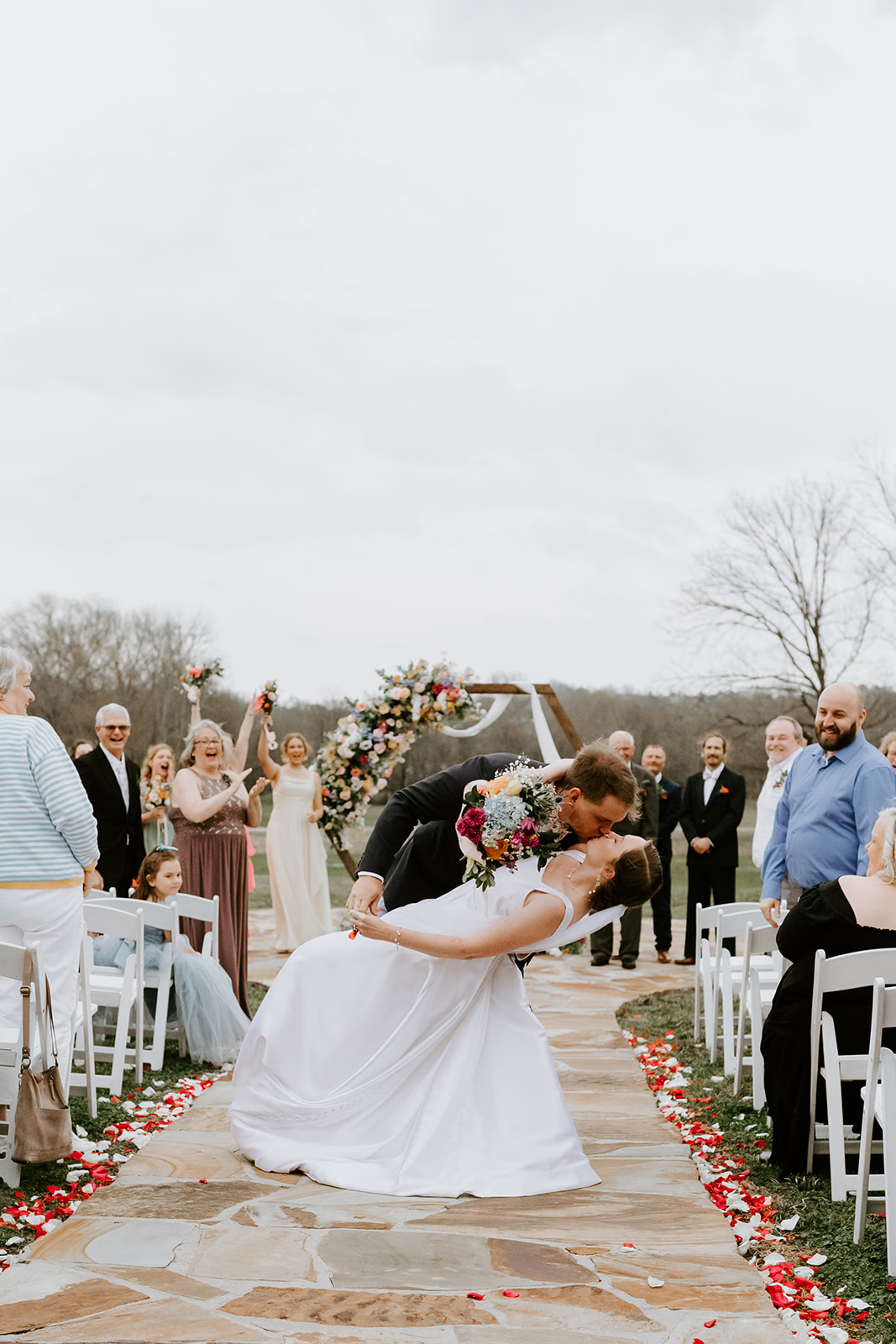 Leslie & Timothy share a dip kiss on the petal-lined aisle after their Covey Creek ceremony