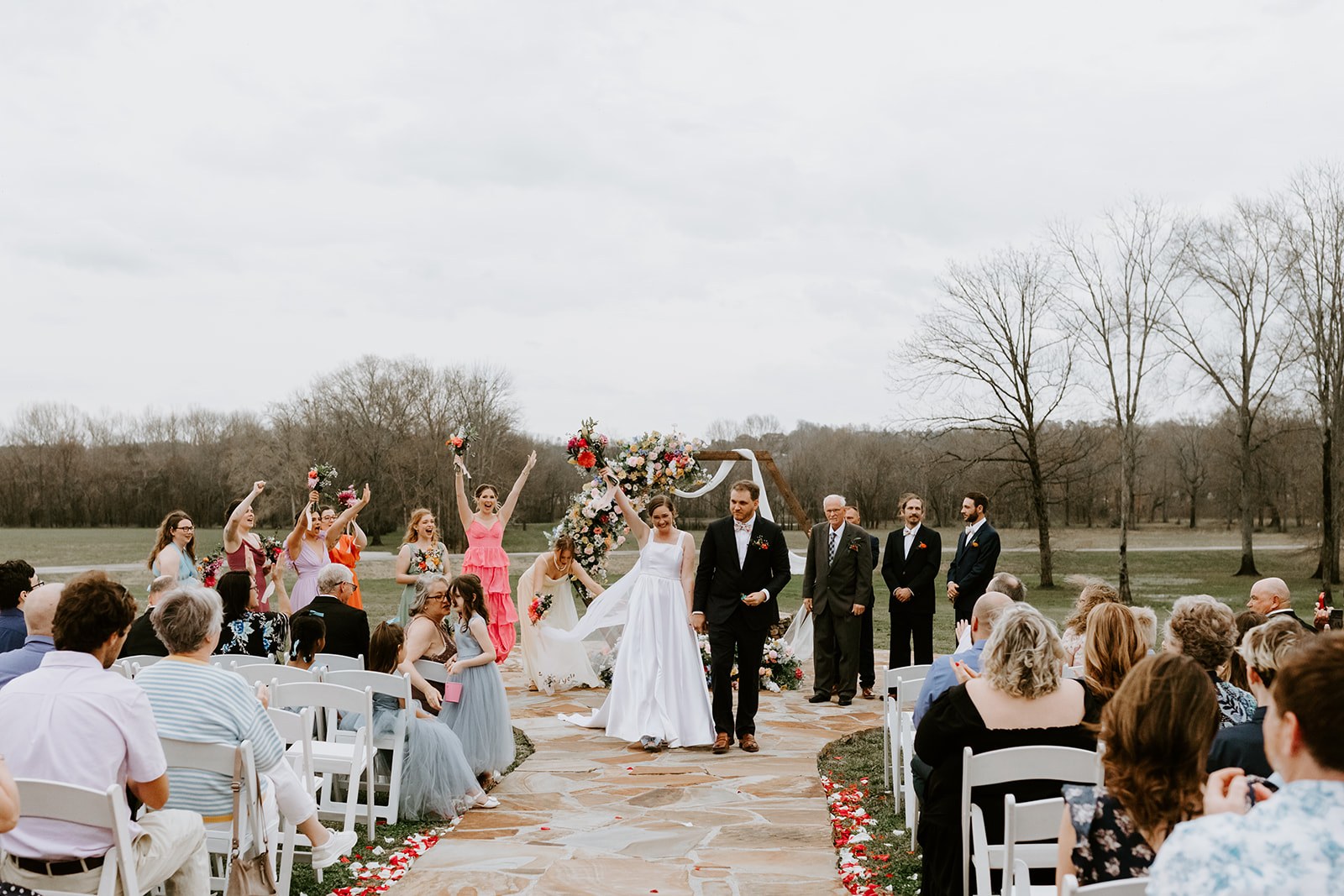Leslie & Timothy recess down petal-strewn stone aisle as guests cheer at Covey Creek ceremony