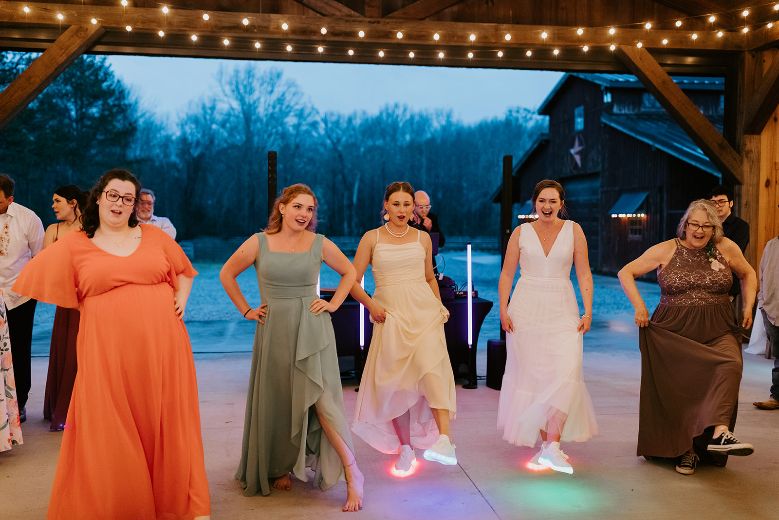 Leslie & Timothy reception guests dance in glowing LED sneakers under Covey Creek pavilion lights