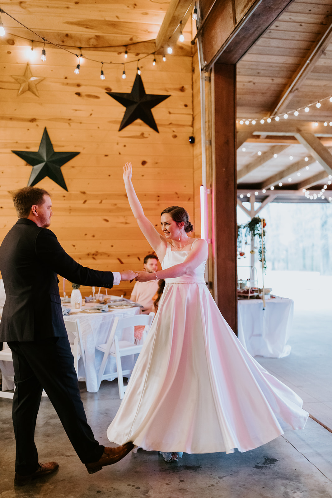 Leslie & Timothy dance as Leslie twirls her gown under string lights at Covey Creek reception