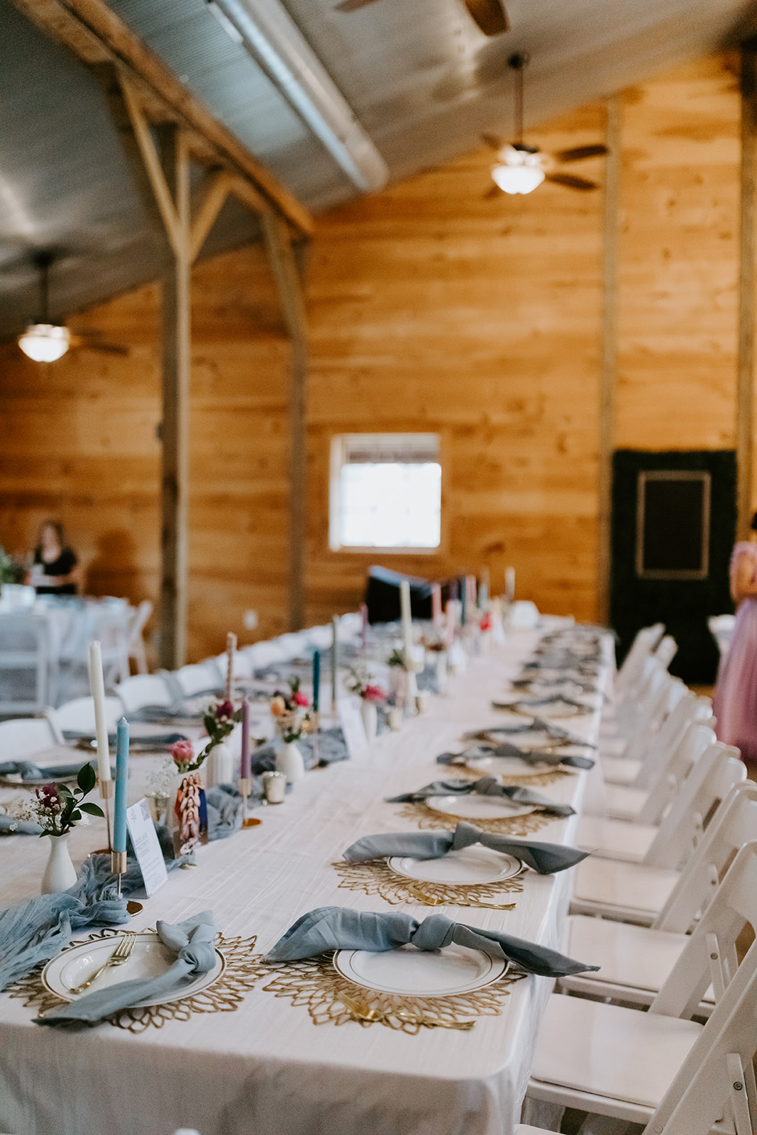 Leslie & Timothy long banquet table with blue runner, taper candles, and gold placemats at Covey Creek