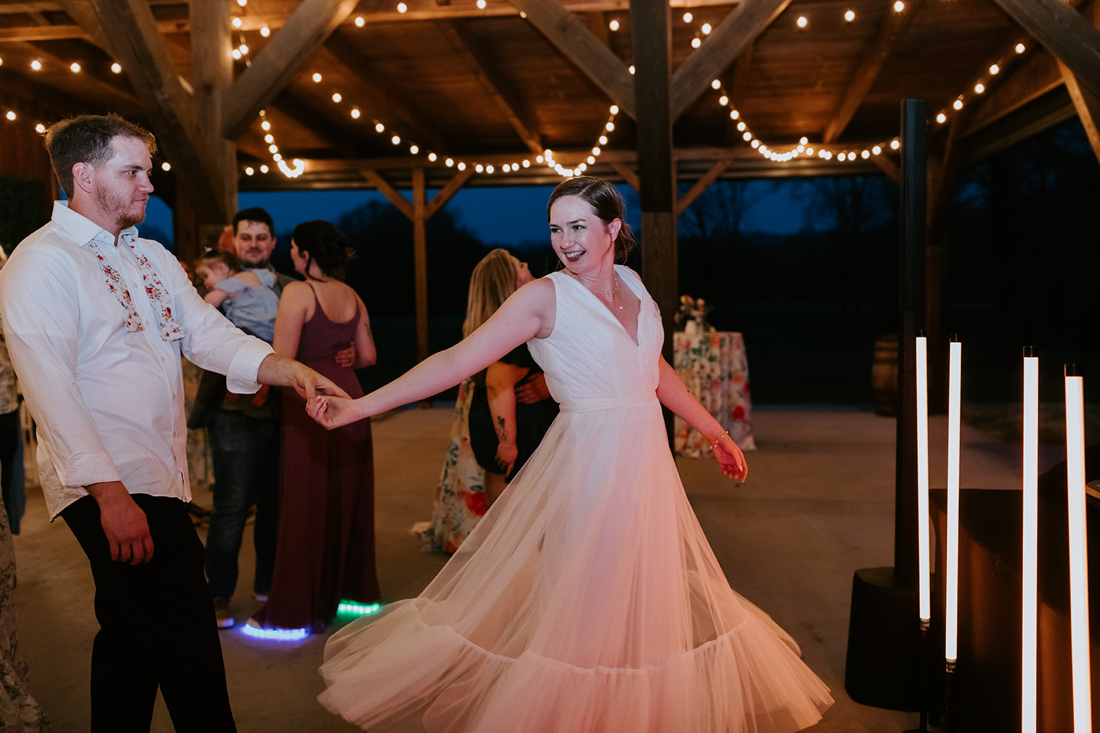 Leslie & Timothy dance under pavilion string lights as her tulle skirt flares at Covey Creek