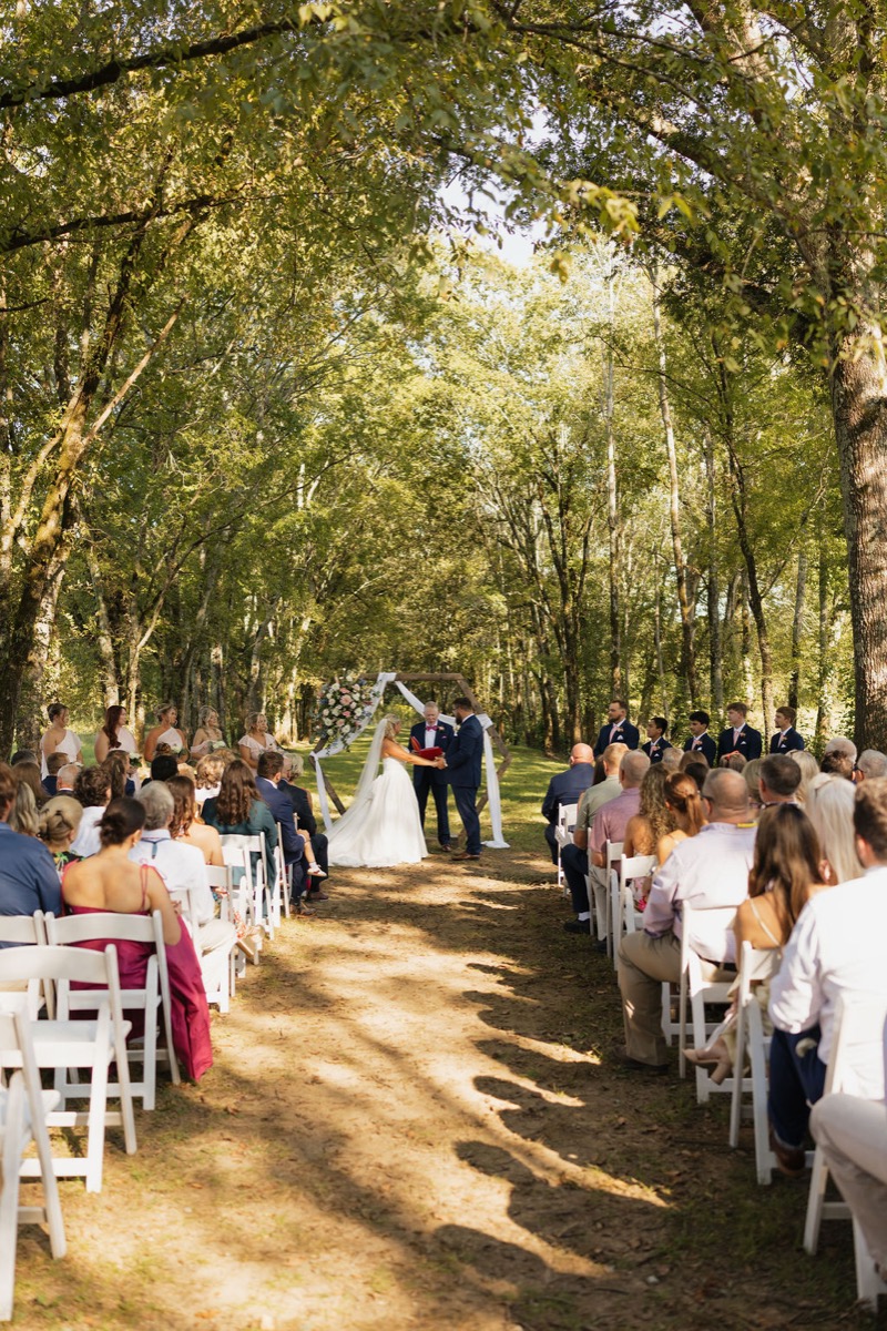 Lilly & Jackson exchange vows under a floral hexagon arbor along the Tunnel of Love aisle at Covey Creek