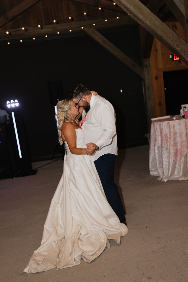 Lilly & Jackson slow dance forehead to forehead under barn string lights at their Covey Creek reception