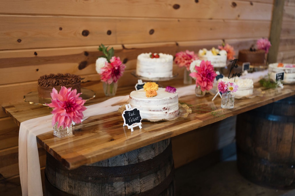 Lilly & Jackson dessert table at Covey Creek with naked red velvet cake, dahlias, and cakes on wooden barrels