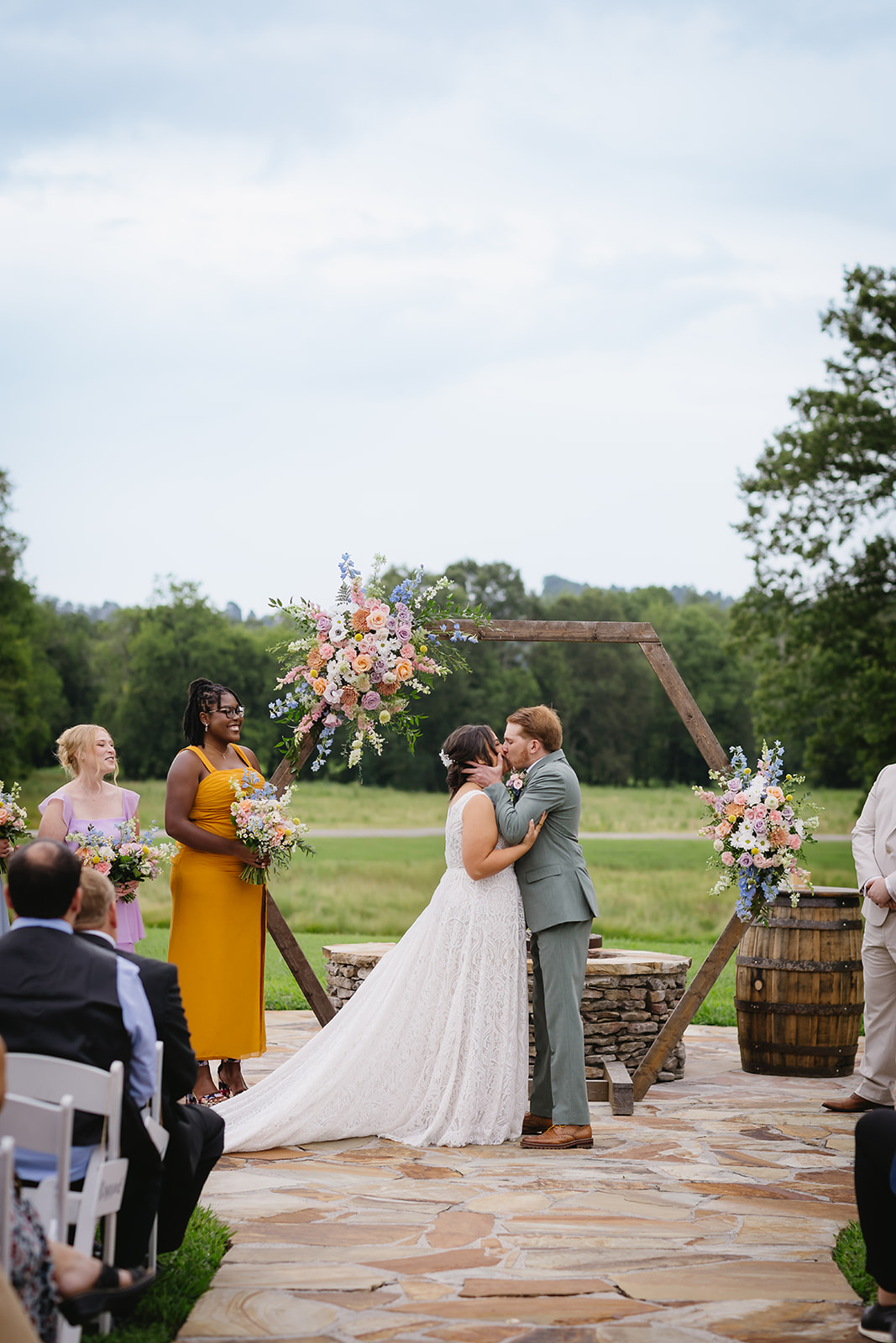 Meredith & Benjamin share a first kiss under the floral hexagon arch on the Patio at Covey Creek