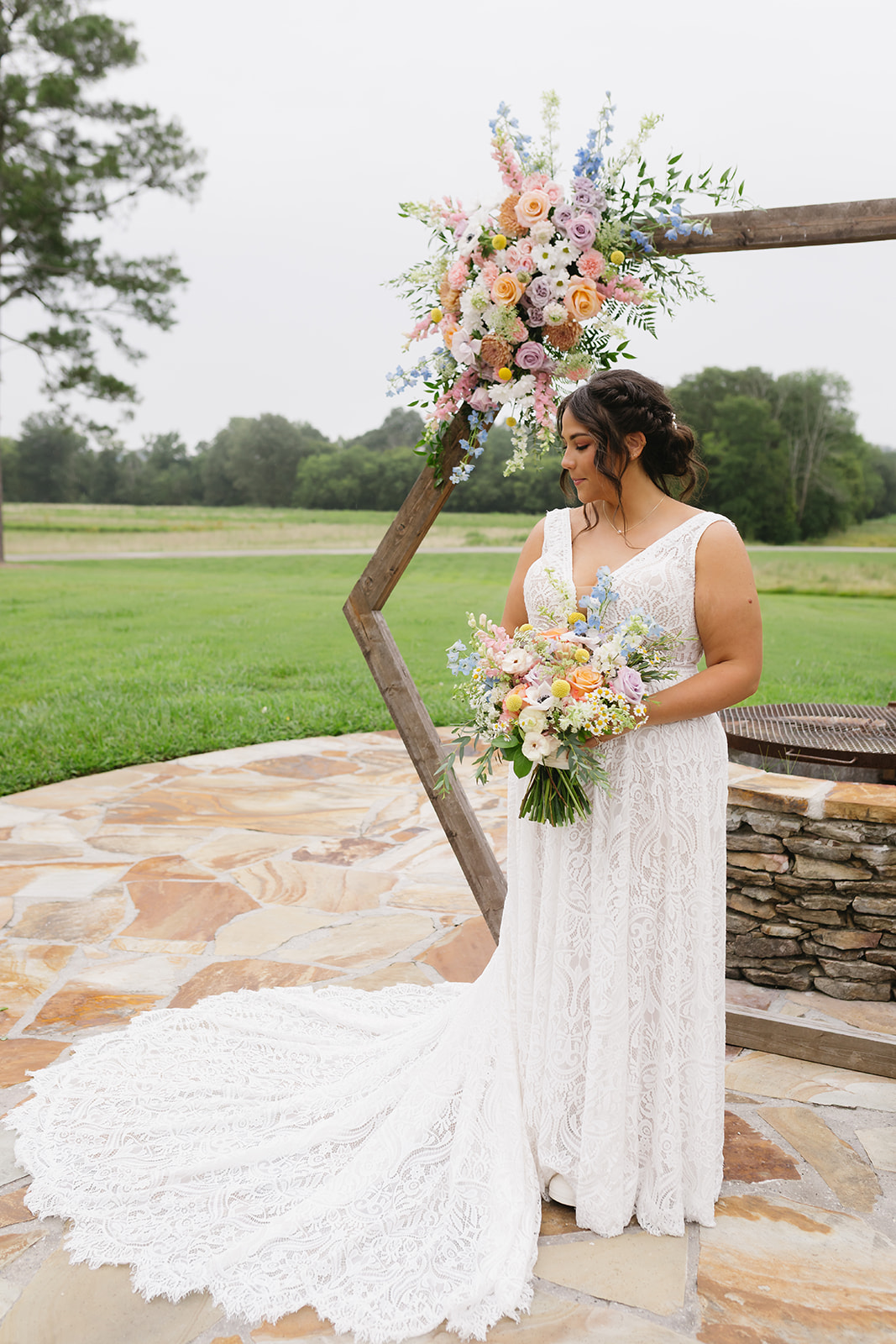 Meredith poses in lace gown before the floral Patio arch for Meredith & Benjamin at Covey Creek