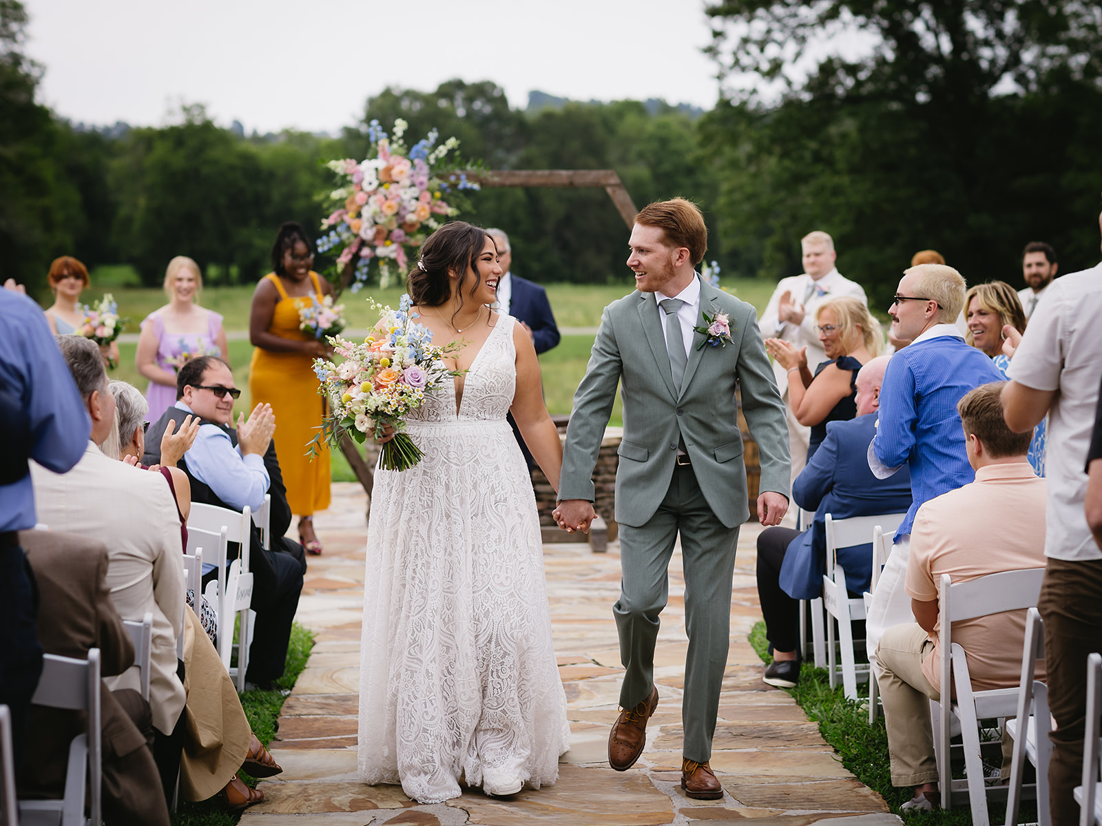 Meredith & Benjamin smile hand-in-hand down the stone aisle after their Patio ceremony at Covey Creek