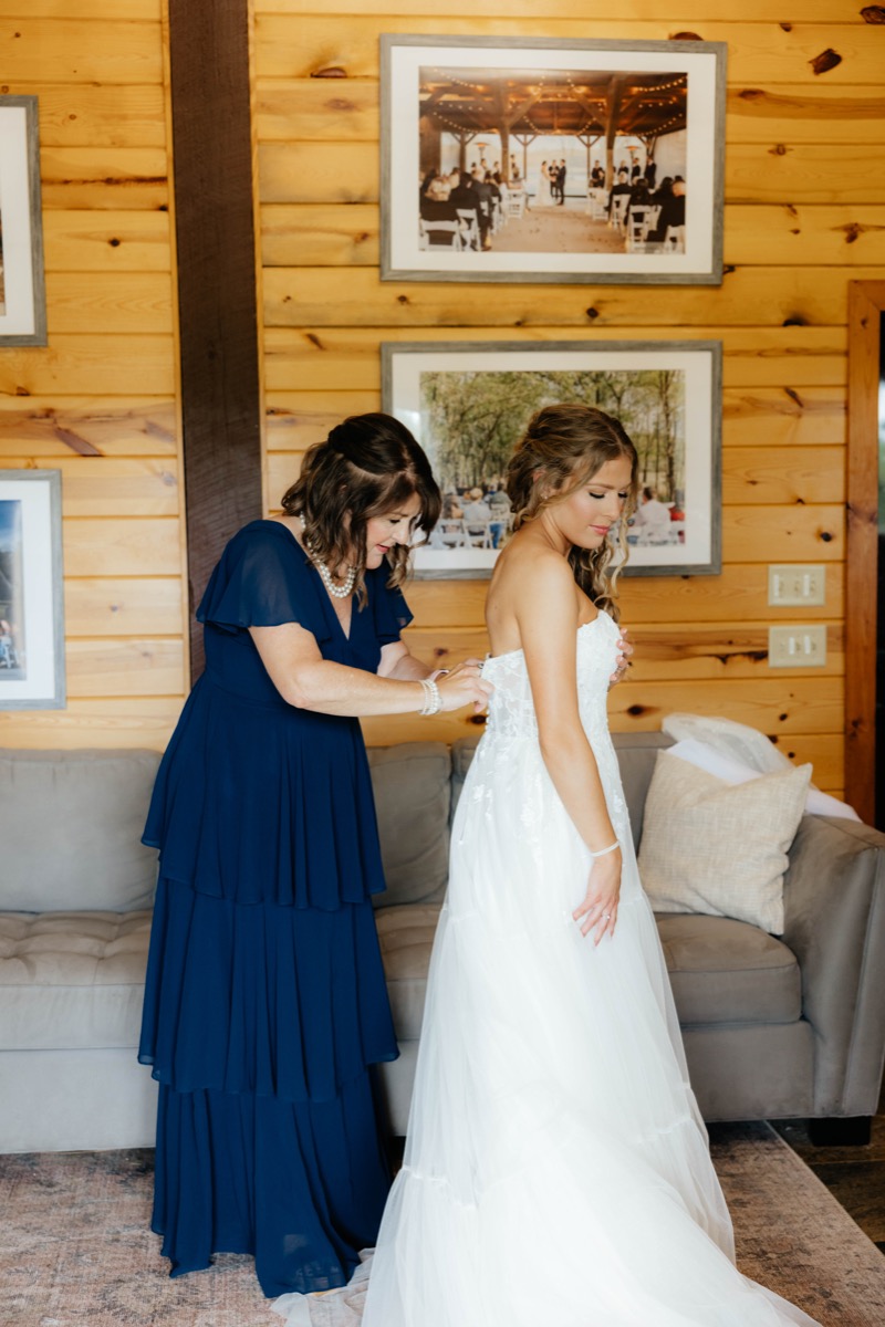 Morgan & Caden bridal prep as a helper buttons her strapless lace gown in Covey Creek’s wood-paneled suite