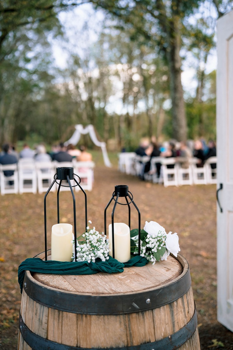 Black lanterns and white florals on a wine barrel frame Peyton & Jackson's outdoor ceremony at Covey Creek.