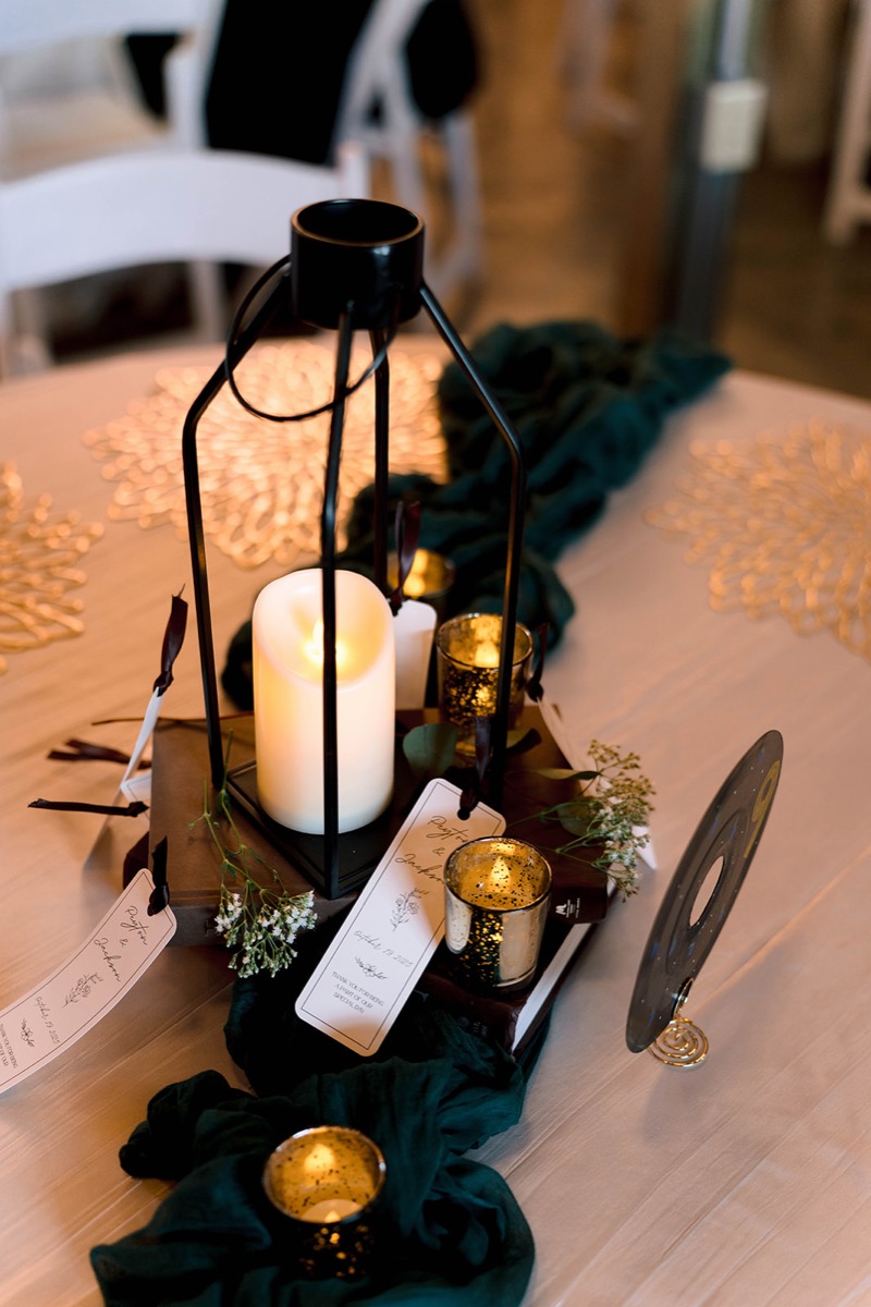 Black lantern, books, and a Peyton & Jackson keepsake tag on a candlelit Covey Creek reception table.