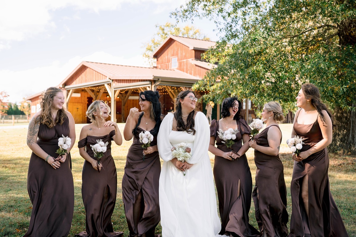 Peyton and her bridesmaids laugh before Covey Creek's barn pavilion at Peyton & Jackson's wedding.