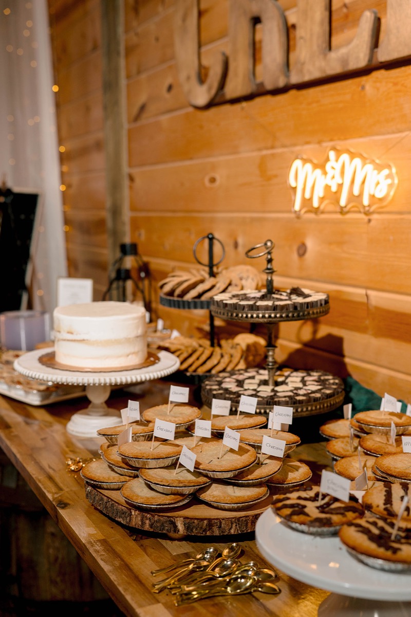 Peyton & Jackson's dessert table with mini pies, cake, and a neon Mr & Mrs sign in Covey Creek's barn.