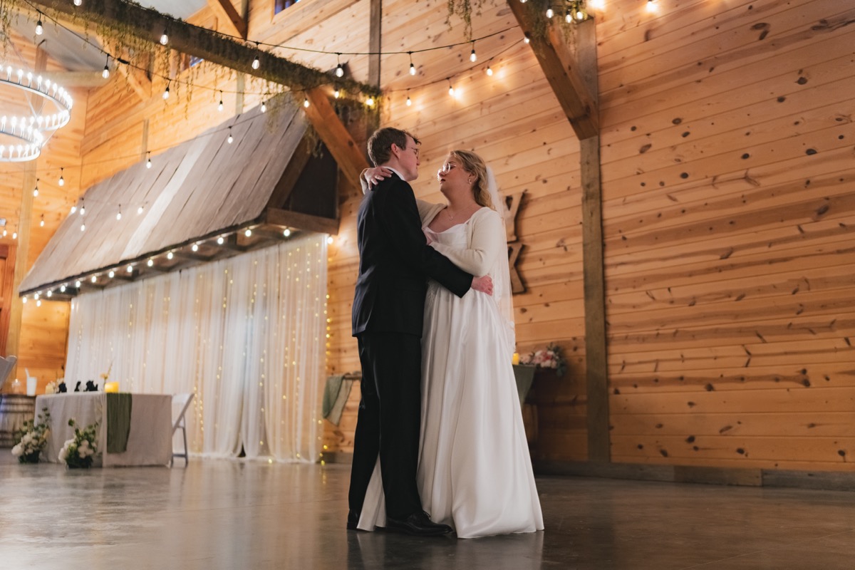 Rae & David share an intimate first dance under string lights in the Covey Creek indoor reception