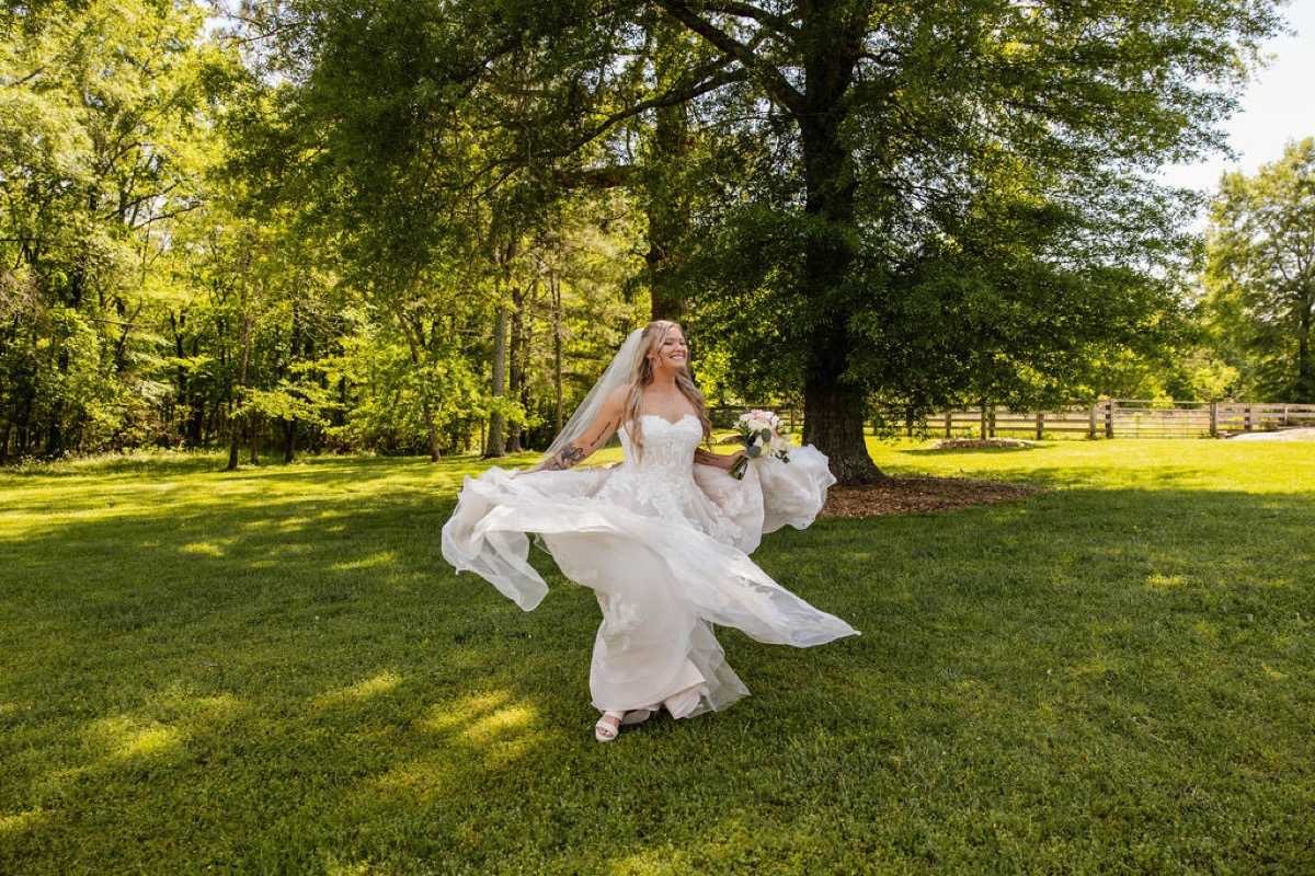 Raven twirls in her strapless lace gown on the sunny green lawn at Covey Creek for Raven & Jackson