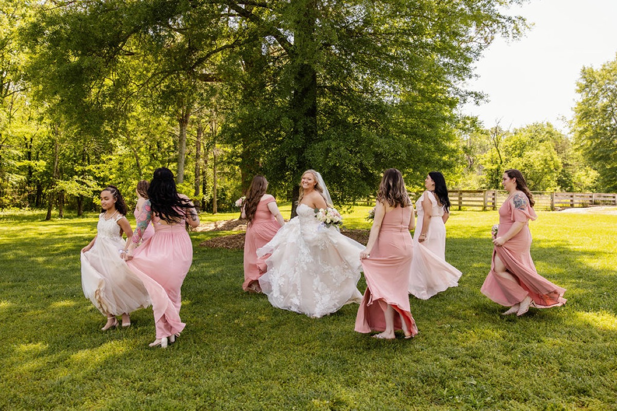 Raven twirls in lace as bridesmaids lift dusty-rose skirts on the lawn at Covey Creek for Raven & Jackson