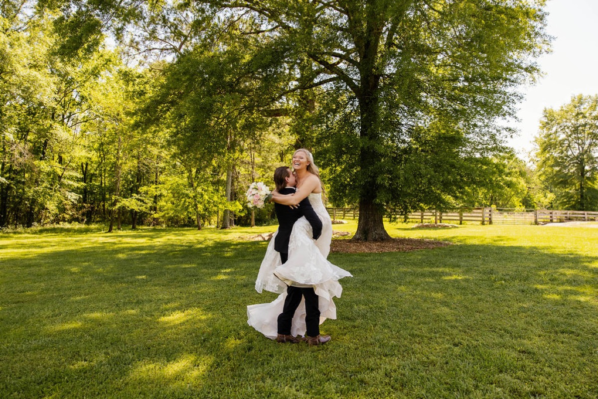 Raven & Jackson spin as Jackson lifts her billowing lace gown on the sunny lawn at Covey Creek