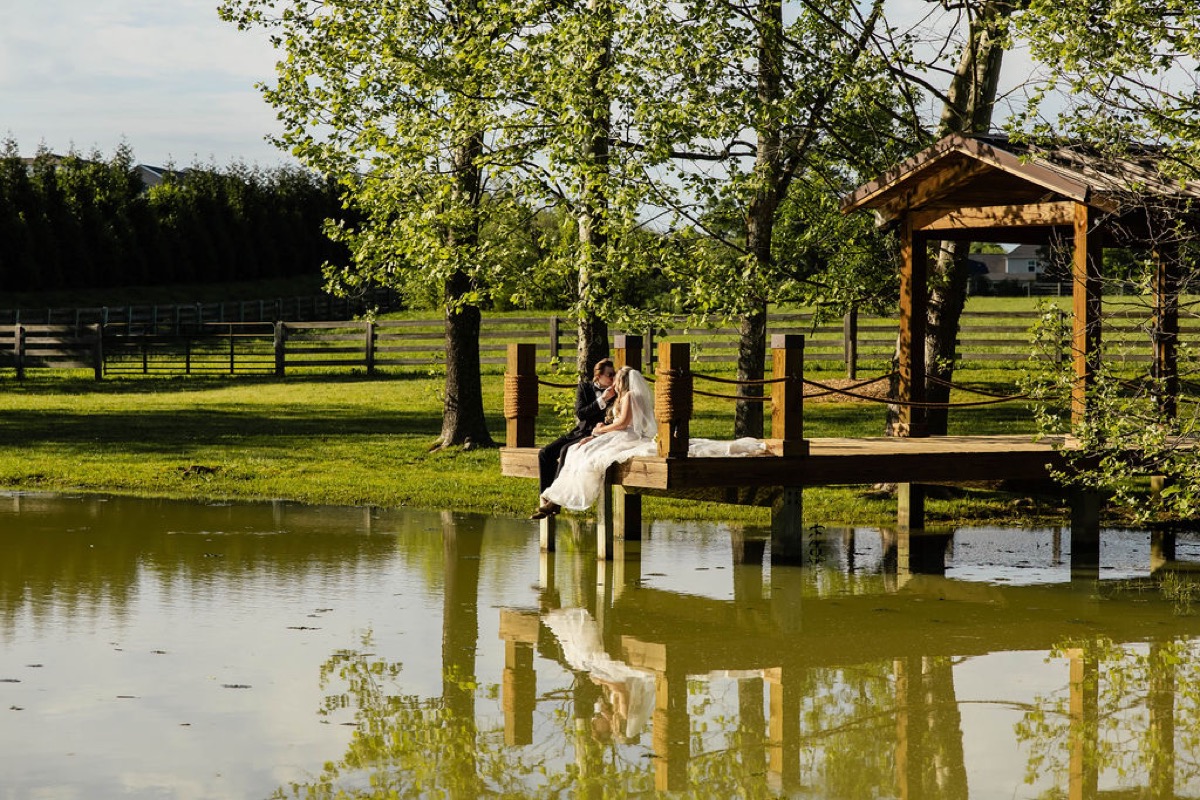 Raven & Jackson lean close on the wooden Pond dock as trees reflect in the water at Covey Creek