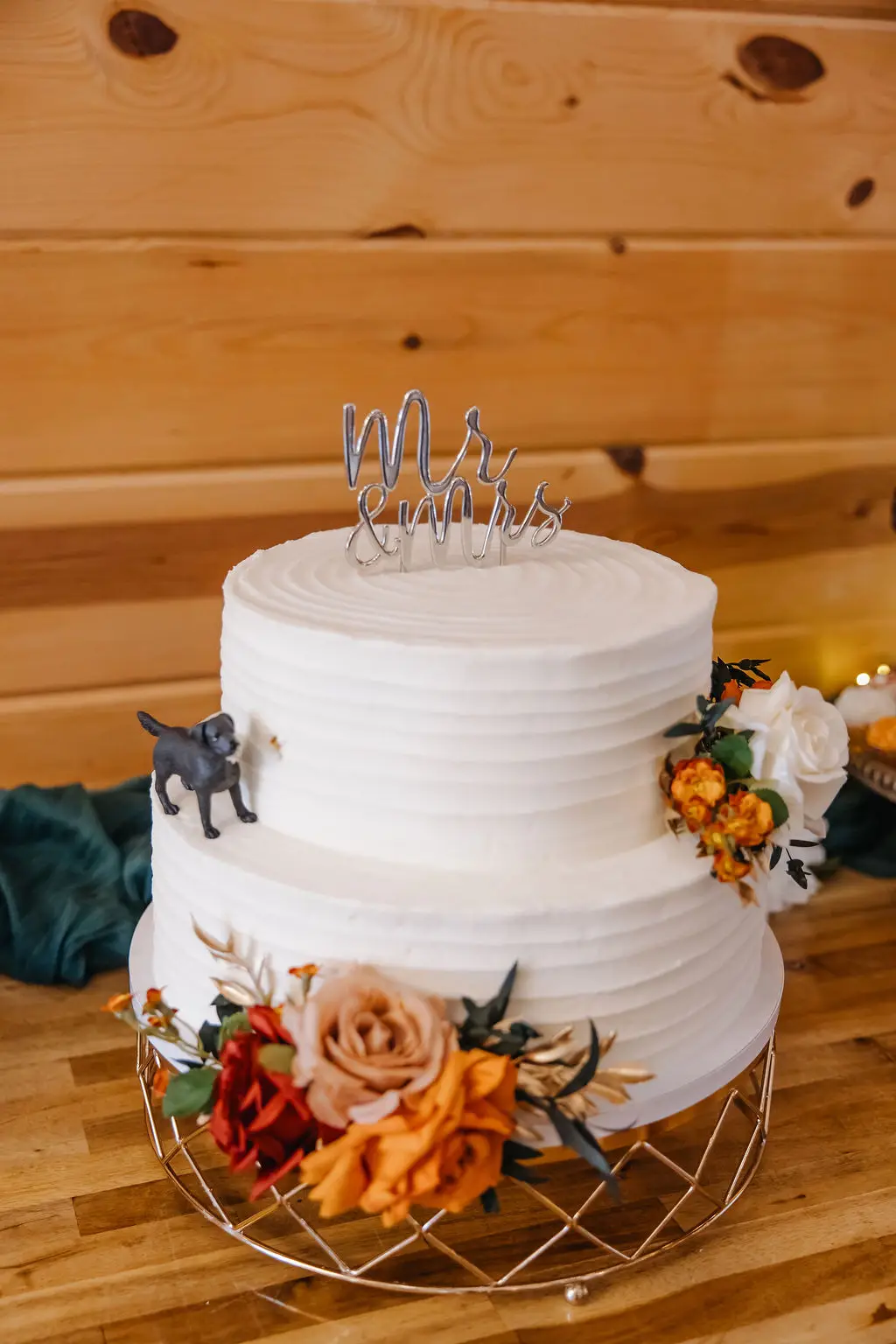 Two-tier white cake with autumn florals, Mr. & Mrs. topper, and dog figurine for Rebecca & Troy at Covey Creek.