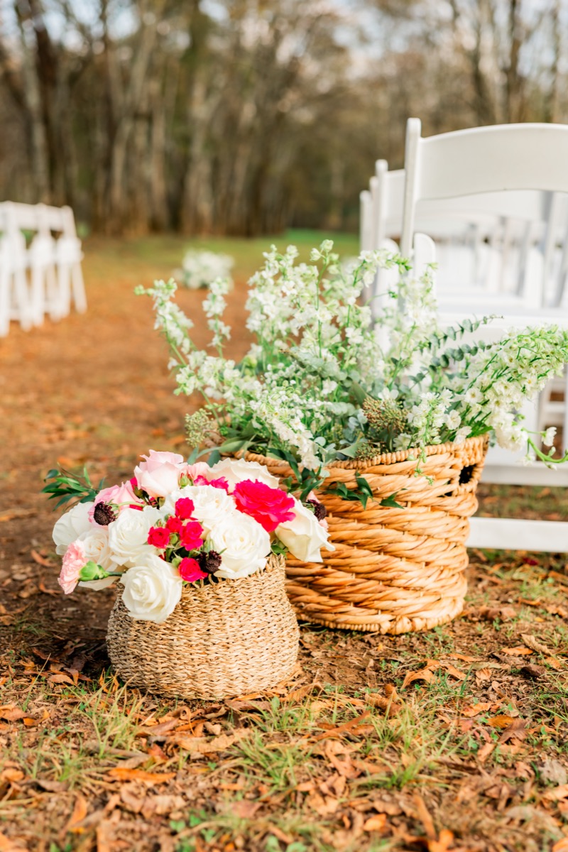 Wicker baskets of pink and white roses mark the ceremony aisle for Sarah & Adam at Covey Creek