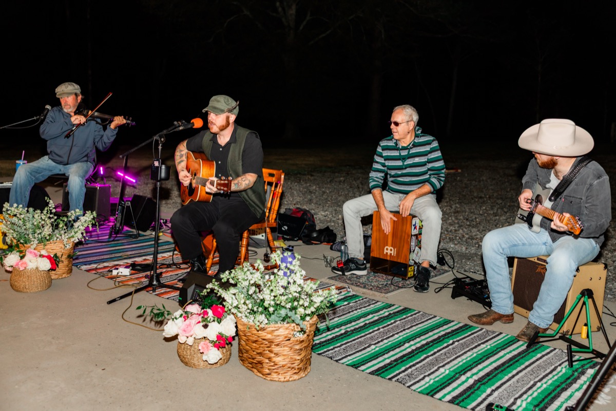 Live band plays on striped rugs beside flower baskets at Sarah & Adam's Covey Creek reception