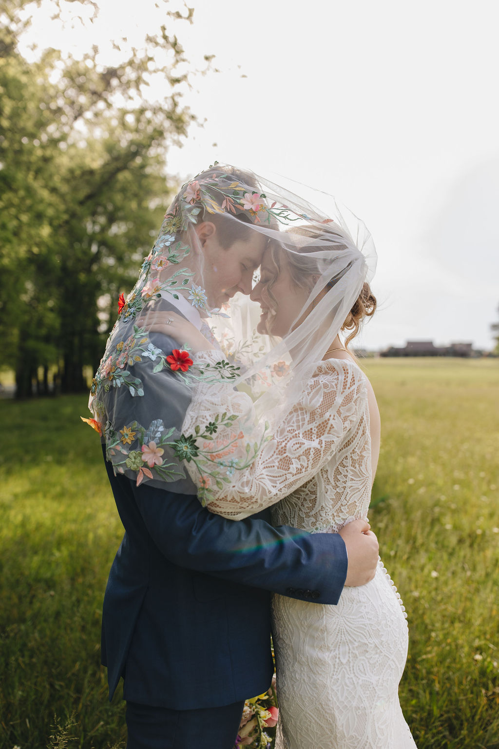 Shay & Jacob share a quiet moment under her embroidered floral veil in a sunlit field at Covey Creek.