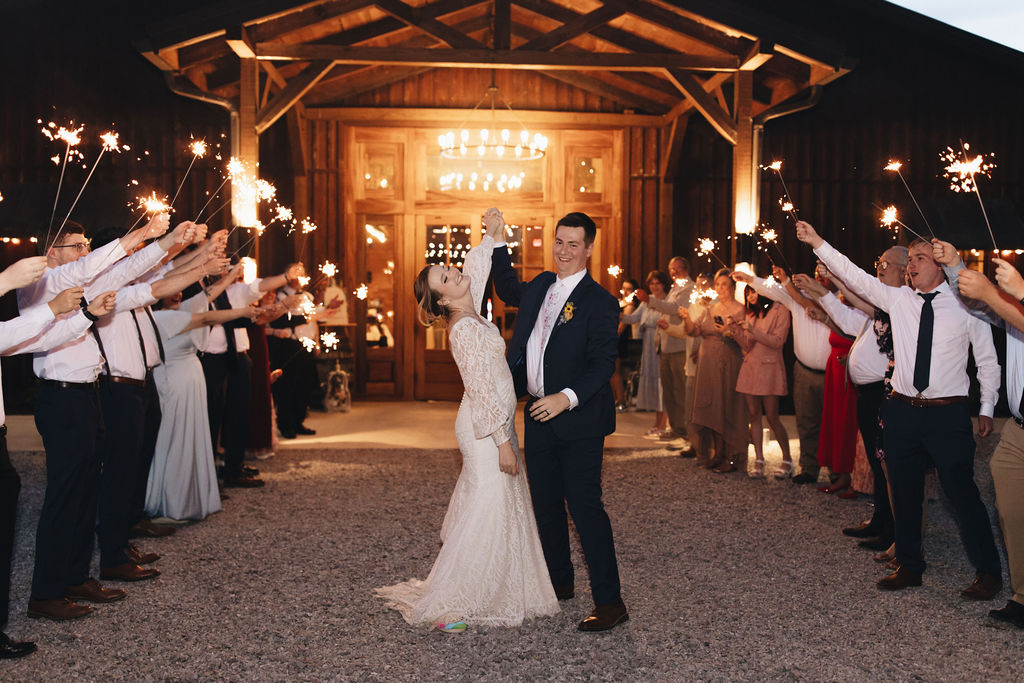 Shay & Jacob dance through a sparkler tunnel before Covey Creek’s lit pavilion, guests lining the gravel path.
