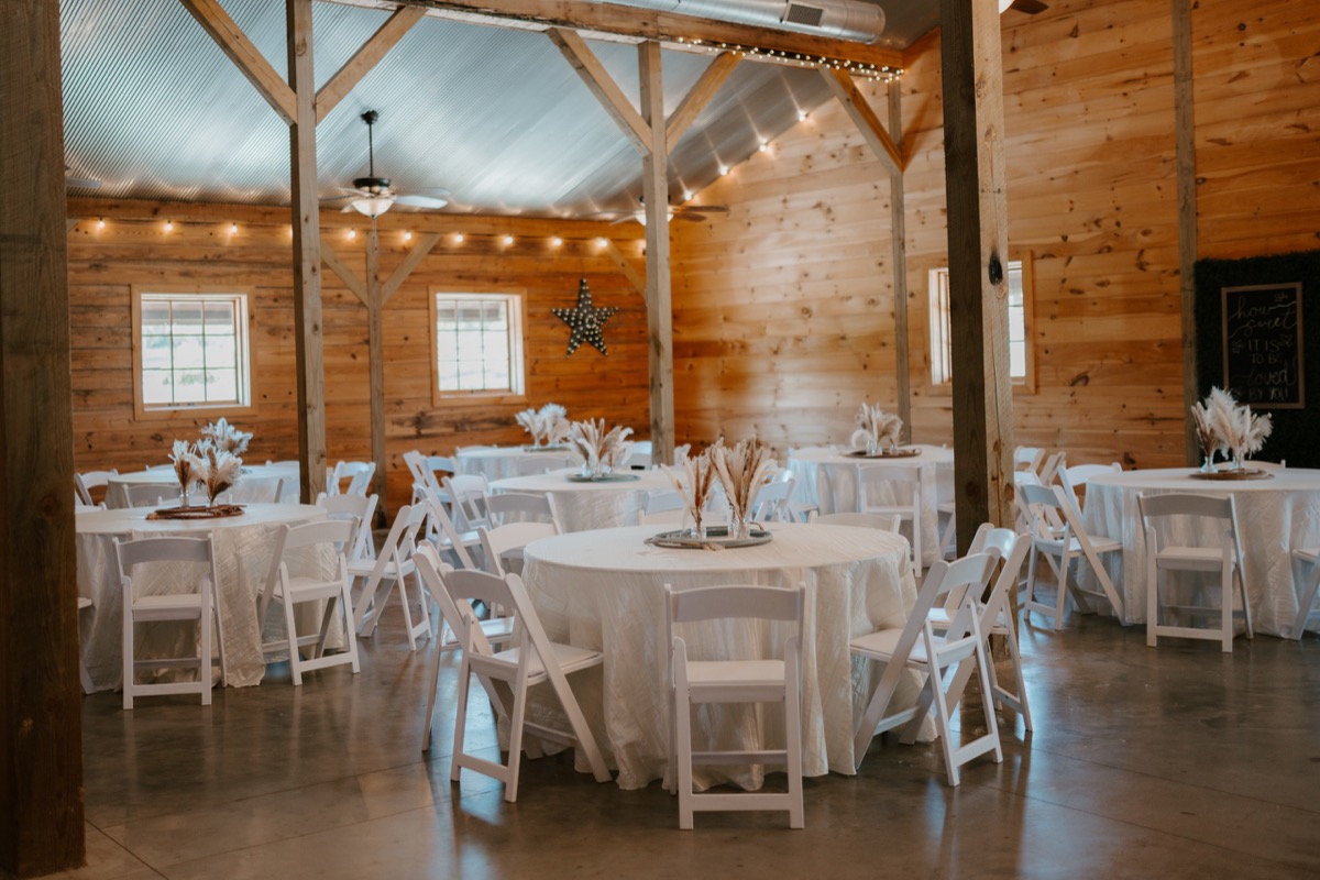 Shay & Wyatt's barn reception at Covey Creek—round white tables, pampas centerpieces, and string lights.