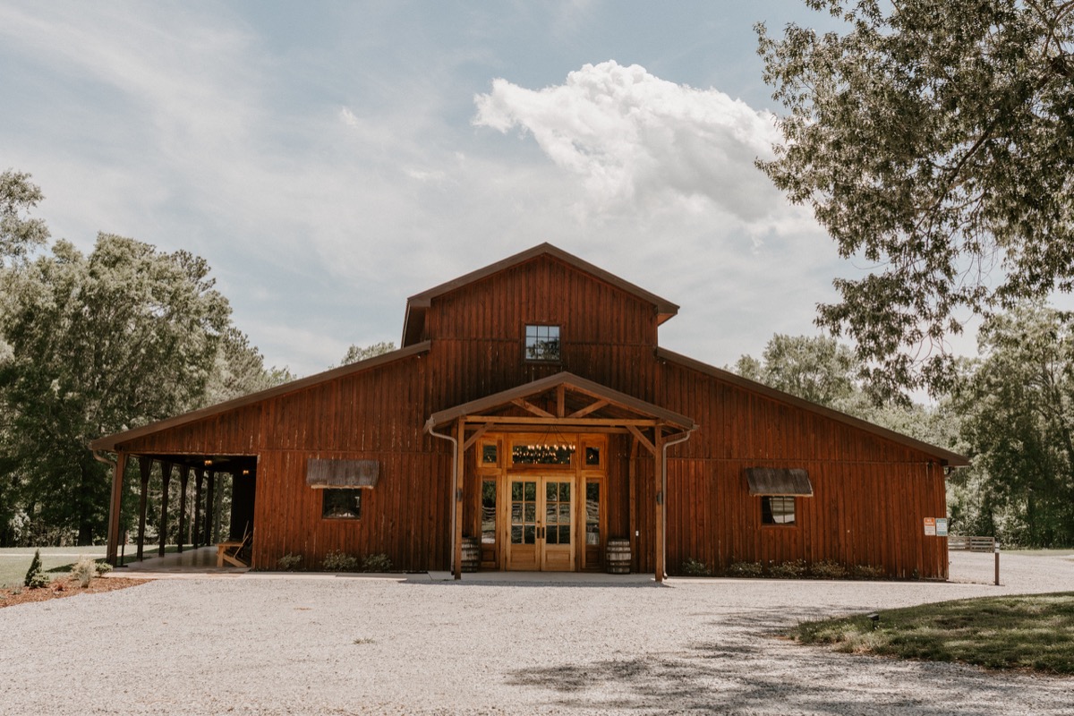 Shay & Wyatt's wedding day at Covey Creek—the dark wood barn with covered entry and gravel drive among trees.