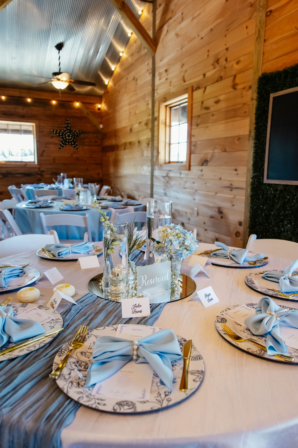 Shelbie & Callaway reception table at Covey Creek with blue floral plates, bow napkins, and floating candles